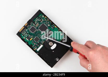 IT-Spezialist mit Schraubendreher repariert alte Computerfestplatte, Bild isoliert auf weißem Hintergrund Stockfoto