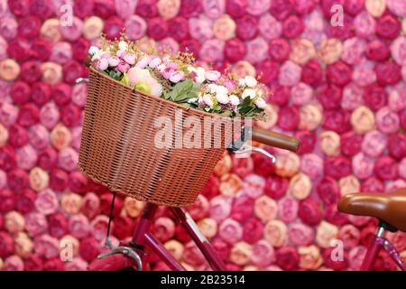 Rosa weiß beige gefärbte Rosen im Korb. Pony aus Papier. Pastellpapier im Hintergrund schöner Stil. Blumen aus Wellpapier als A. Stockfoto