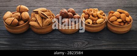 Nussset in einer Schüssel auf schwarzem Holzhintergrund Stockfoto