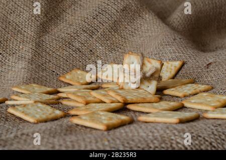 Gesalzene Cracker auf Burlap Hintergrund. Knusprige Leckereien. Glutenfreie, gesunde Lebensmittel. Aufnahmen auf Augenhöhe. Selektiver Fokus. Nahaufnahme. Stockfoto