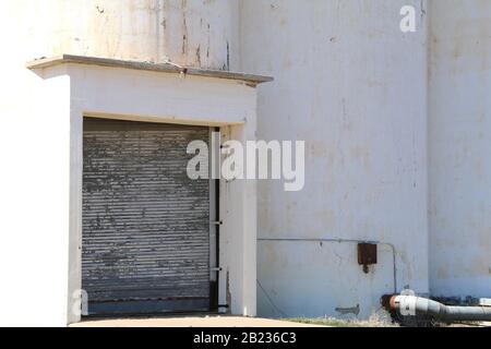 Ein weißes Farm-Silo-Gebäude, das am Nachmittag die Tür lädt Stockfoto