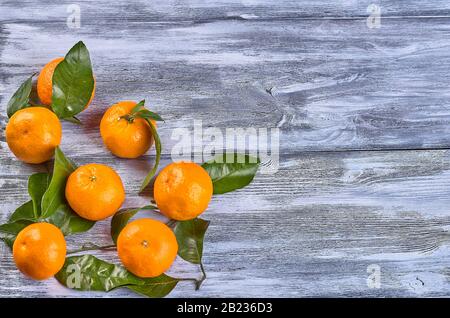 Mandarinen Reife, saftige Mandarinen mit Blättern auf grauem Holzhintergrund. Platz für die Inscriptionon auf grauem Holzhintergrund Stockfoto