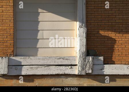 Eine Schiffstür in einem verlassenen Ziegellager an einem sonnigen Nachmittag mit Schatten Stockfoto