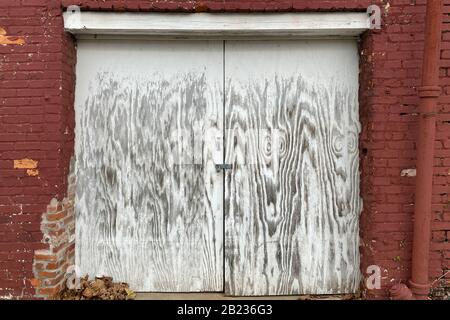 Ein Paar verblichener weiß lackierter verschlossener Versand- und Warenannahme an einem roten Backallee-Lagerhaus Stockfoto