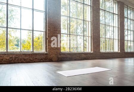 Weiße Matte auf Holzboden im modernen Fitnessstudio. Stockfoto