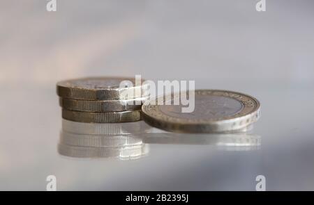 Britische Pfund und ein £2-Münzschuss-Makro auf einer reflektierenden Oberfläche Stockfoto