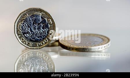 Britische Pfund und ein £2-Münzschuss-Makro auf einer reflektierenden Oberfläche Stockfoto