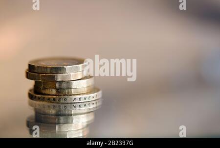 Britische Pfund und ein £2-Münzschuss-Makro auf einer reflektierenden Oberfläche Stockfoto