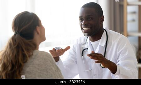 Lächelnder afroamerikanischer Arzt, der bei einem Treffen eine weibliche Patientin berät Stockfoto