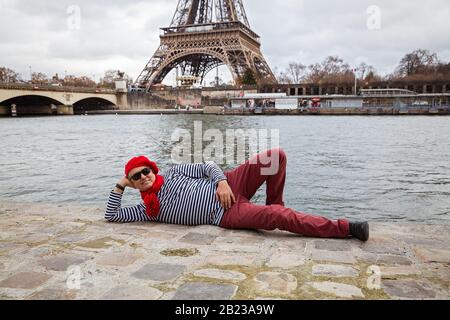Der Mensch liegt am Ufer vor dem Hintergrund des Eiffelturms Stockfoto
