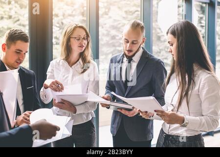 Sechs junge Geschäftsleute analysieren die Ergebnisse und diskutieren sie. Eine Gruppe von Mitarbeitern, die an einem Projekt im Büro arbeiten Stockfoto