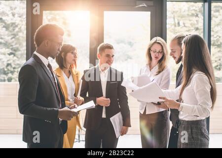Sechs junge Geschäftsleute analysieren die Ergebnisse und diskutieren sie. Eine Gruppe von Mitarbeitern, die an einem Projekt im Büro arbeiten Stockfoto