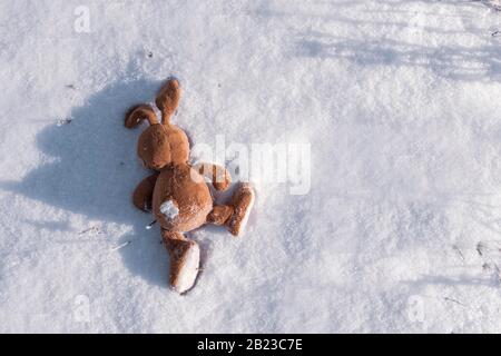 Verlassene Hase Spielzeuge liegen auf dem Schnee. Copyspace. Kinder verlieren und werfen Spielzeug. Allegorie, Trennung, Einsamkeit und Tod. Stockfoto