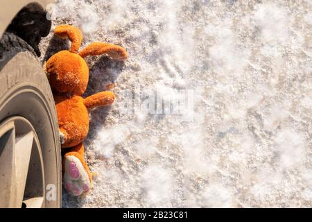 Kinderunfall auf einer Winterstraße, Hase Kaninchen Spielzeug. Tod auf der Straße, Unachtsamkeit und Gefahr. Achtung und Vorsicht. ROADKILL Winter, Konzept. C Stockfoto