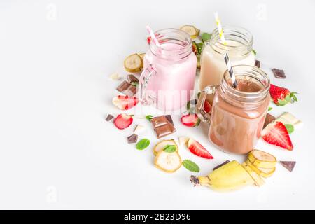 Drei Maurer-Gläser mit Milchshakes oder Smoothie. Sommer gesundes Frühstück, Mittagessen Getränke - Bananen, Schokolade und Erdbeermilchshakes auf Holzbackgroun Stockfoto