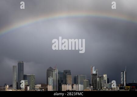 London, Großbritannien. Februar 2020. Wetter in Großbritannien: Ein massiver Regenbogen bricht über dem Osten Londons nach einem kurzen Regensturm am Nachmittag über die Gebäude des Canary Wharf Business Parks. Credit: Guy Corbishley/Alamy Live News Stockfoto