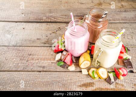 Drei Maurer-Gläser mit Milchshakes oder Smoothie. Sommer gesundes Frühstück, Mittagessen Getränke - Bananen, Schokolade und Erdbeermilchshakes auf Holzbackgroun Stockfoto