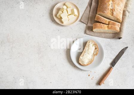 Brot und Butter auf weißem Tisch, Kopierraum. Frisches Ciabatta Brot und Biobutter zum Frühstück. Stockfoto