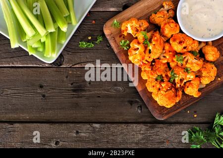 Büffelflügel mit Blumenkohl. Tisch-Szene in Draufsicht vor einem Holzhintergrund mit Kopierbereich. Gesundes Essen, pflanzliches Fleisch Ersatzkonzept. Stockfoto