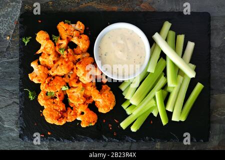 Büffelflügel mit Blumenkohl und Sellerie. Draufsicht auf einer Servierplatte aus Schiefer. Gesundes Essen, pflanzliches Fleisch Ersatzkonzept. Stockfoto