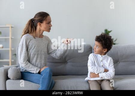 Wütende strenge Mutter schimpft den frechen kleinen afroamerikanischen Jungen Stockfoto