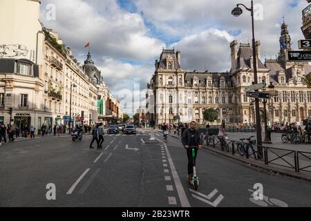 Paris, Frankreich - 30. September 2019: Mann auf einem E-Roller, der am Rathaus (Hotel de ville) vorbeifährt, Radweg in der Rue de Rivoli Stockfoto
