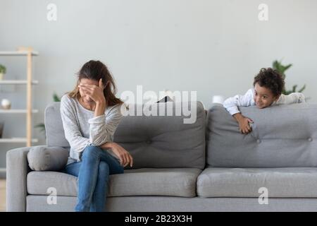 Verärgerte Frau, die an einem hastigen afroamerikanischen Jungen schlechtes Verhalten leidet Stockfoto