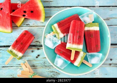 Hausgemachte Wassermelonenpopskel auf einem Teller. Draufsicht auf einem rustikalen blauen Holzhintergrund. Sommernahrungskonzept. Stockfoto