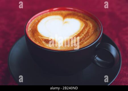 Tasse Kaffee mit Herzform auf pinkfarbenem Hintergrund. Stockfoto