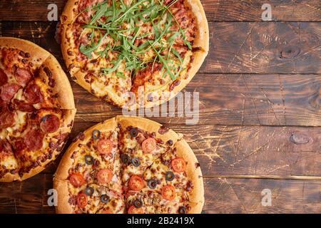 Zusammensetzung von drei verschiedenen Arten Pizza auf hölzernen Tisch Stockfoto