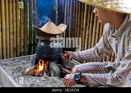 Traditioneller Reiskocher über offenem Feuer, klebrige Reisküche in einem Bambuskorb über schimmerndem Wasser, Lebendes Land Rice Farrm, Luang Prabang, Laos Stockfoto
