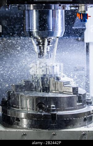 Vertikales Foto des industriellen Nassfräsprozesses in 5-Achs cnc Maschine mit Kühlmittelfluss unter Druck und eingefroren Spritzer Stockfoto