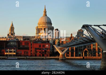 Ein Landschaftsbild der St Paul's Cathedral und der Millennium Bridge London vom gegenüberliegenden Ufer der Themse bei Sonnenuntergang. Stockfoto