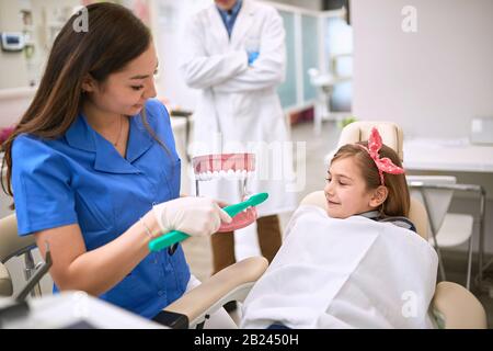 Zahnärztin zeigt Kindern auf dem Kiefermodell, wie sie ihre Zähne richtig putzen Stockfoto