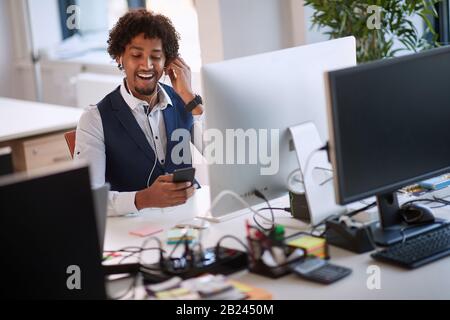 Erfolgreicher afroamerikanischer Geschäftsmann, der einen Handyanruf hält. Junge Geschäftsleute im Büro. Stockfoto