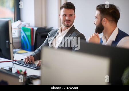 Junge Geschäftskollegen Männer sprechen bei der Arbeit im modernen Büro. Stockfoto