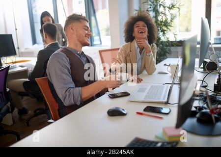 Geschäftsleute, die ein Meeting führen. Verschiedene Designerkollegs lächeln im modernen Büro. Stockfoto