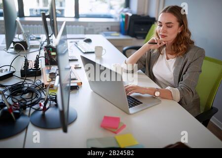 Fachfrau, die an Geschäftsplänen auf einem Laptop arbeitet. Stockfoto