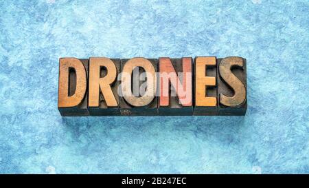 Drohnen sprechen abstrakt in Vintage Letterpress-Holzart gegen blaues Strukturpapier, Technologiekonzept Stockfoto