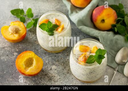 Natürliche Entgiftung, Fruchtdessert, gesundes Ernährungskonzept. Pfirsichjoghurt Smoothie oder Milchshake mit chia Samen im Glasbecher auf einem Betonarbeitsplatt aus Stein. Stockfoto