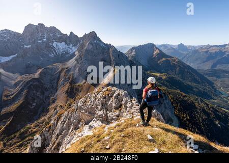 Junge Frau, Bergsteigerin mit Kletterhelm mit Blick auf die Berglandschaft, Wanderung zur Ehrwalder Sonnenspitze, hinter Gruenstein und West Stockfoto