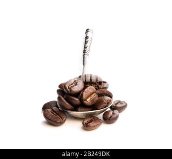 Gebratene Kaffeebohnen in kleinem Silberlöffel isoliert auf Weiß Stockfoto