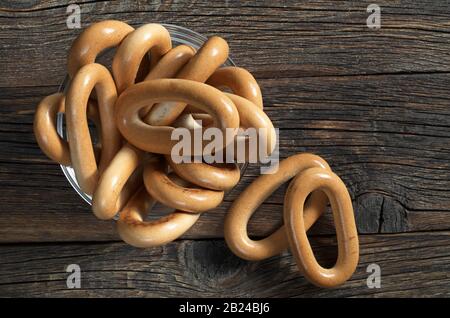 Ovale Bagels in Glasschale auf altem Holztisch, Draufsicht Stockfoto