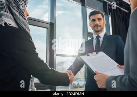 Professioneller arabischer Geschäftsmann schüttelt mit dem Partner die Hände, um sich mit dem Übersetzer im Büro zu treffen Stockfoto