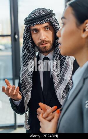 Selektiver Fokus arabischer Unternehmer im Gespräch mit Geschäftsfrau im modernen Büro Stockfoto