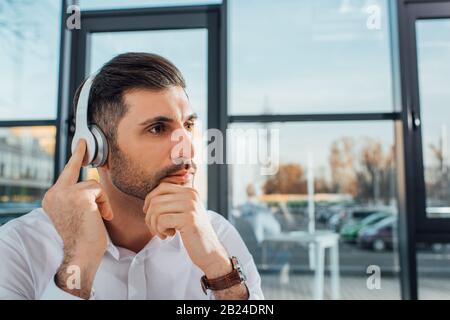 Professioneller männlicher Übersetzer in Brillen, der online mit Kopfhörern arbeitet Stockfoto