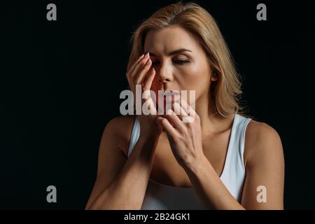 Frau berührt verletzte Hand isoliert auf Schwarz Stockfoto