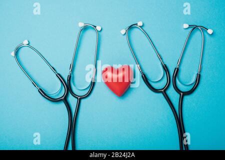 Draufsicht auf dekoratives rotes Herz mit Stethoskopen auf blauem Hintergrund, Weltgesundheitskonzept Stockfoto