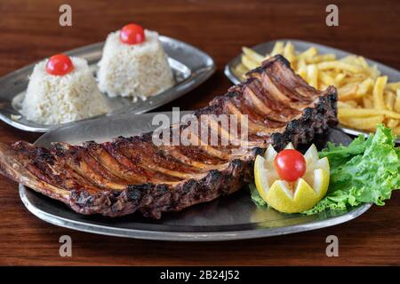 Amerikanisches Gericht, gegrillte Rippen mit Reis und Kartoffeln. Auf einem Holztisch Stockfoto