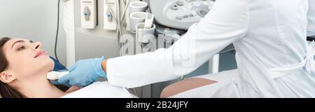 Panoramaaufnahme des Arztes, der die Schilddrüse weiblicher Patienten mit Ultraschalluntersuchung in der Klinik untersucht Stockfoto
